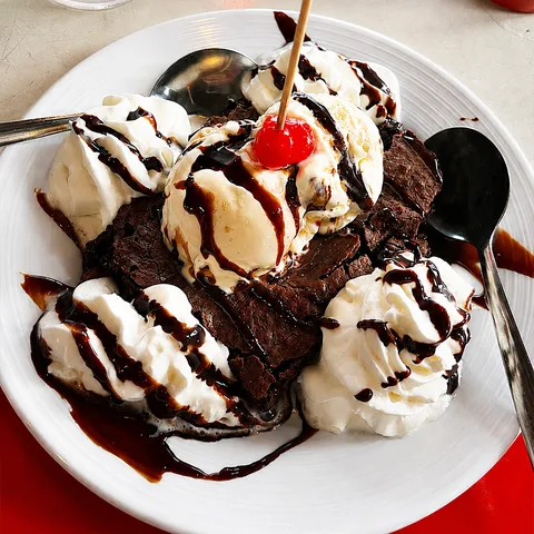 Chocolate brownie sundae with vanilla ice cream, chocolate sauce, whipped cream and a cherry