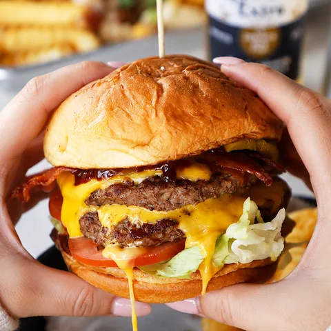 Double-patty burger with lettuce, tomato and pickles on a sweet bun